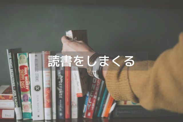 多くの本の中で一冊の本を出す女性の手