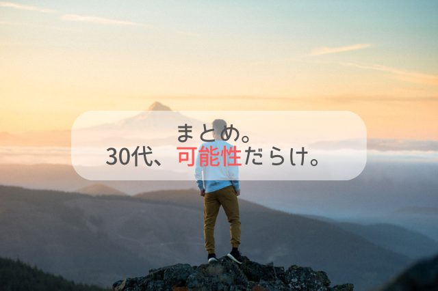 朝焼けの中、壮大な山の景色を背景に、頂上に立っている男性の後ろ姿。