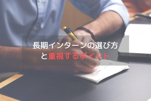 机の上で紙に何かを書いているスーツを着た男性