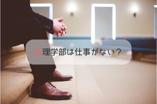 階段に座って膝に肘をついているスーツ姿の男性の足もと