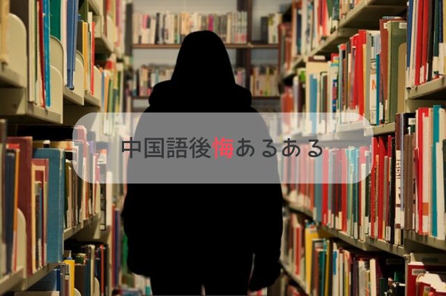 図書室の本に囲まれて立っている真っ黒なーパーカーを着てフードを被った人間の後ろ姿